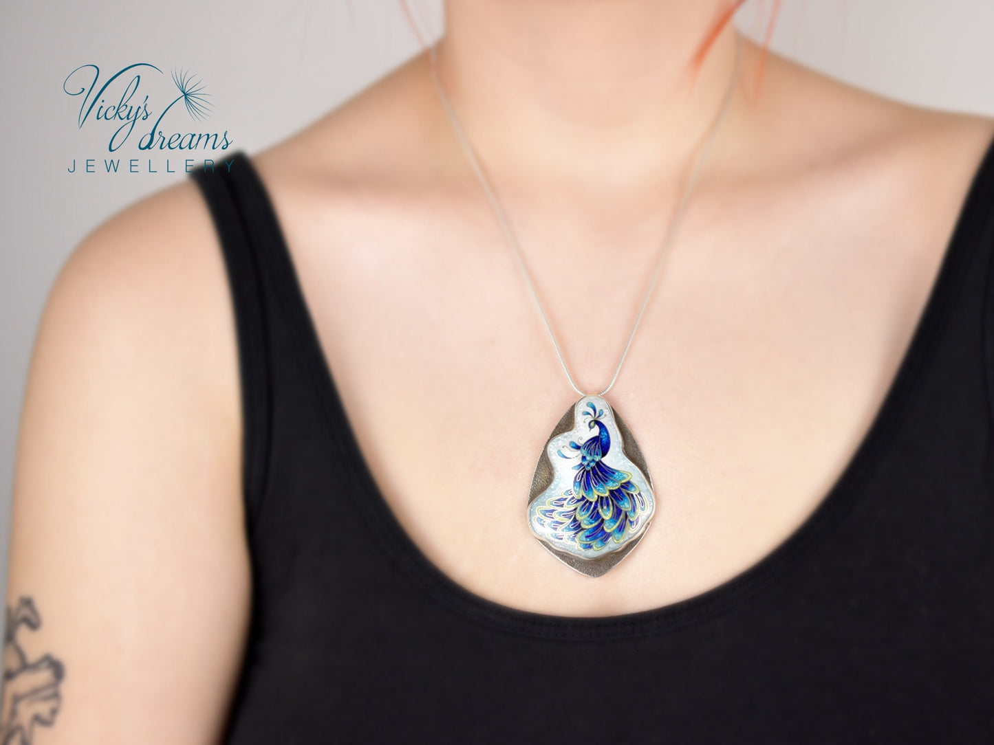 Handmade sterling silver peacock pendant with colorful enamel and artistic design.